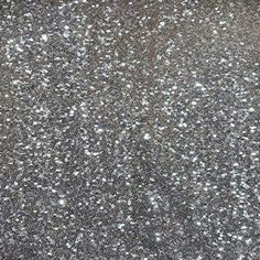 a close up view of the surface of an asphalt driveway with white and silver speckles