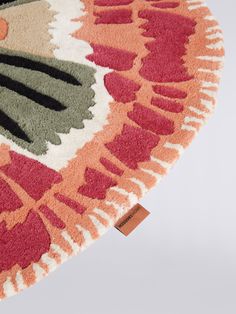 a round rug with an orange, green and red design on it's surface