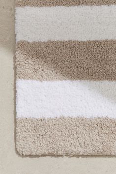 a white and brown striped rug on top of a carpeted floor next to a toilet