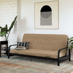 a living room with a blue futon couch and potted plant