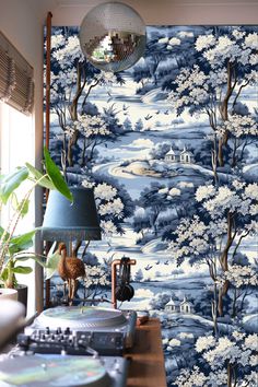 a room with blue and white wallpaper that has trees on it, along with record players