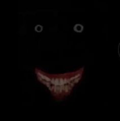 the face of a person wearing a creepy mask in the dark with eyes and teeth