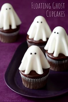 chocolate cupcakes decorated with white icing and spooky ghost decorations on a purple plate