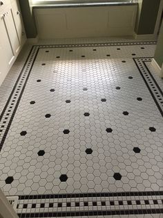 a bathroom floor with black and white tiles on it's sides, in front of a window