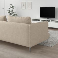 a living room with a couch, television and rugs on the floor in front of it