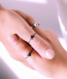 a woman's hand with a ring on it and a small cross tattoo on the middle finger