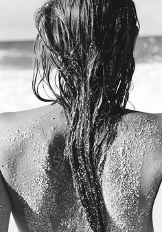 the back of a woman's head covered in sand