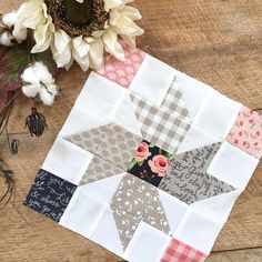 a close up of a patchwork quilt on a wooden surface with flowers and scissors