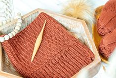 a knitting kit in a wooden box with beads and yarn on the floor next to it