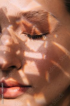 a woman's face is shown through the shadows of her shadow - covered eyes