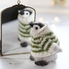 two small knitted animals sitting in front of a mirror