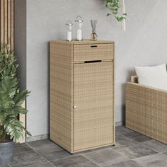 a wicker cabinet sitting next to a plant