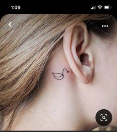 a woman's ear with a small bird tattoo on it