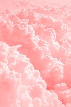 the sky is filled with fluffy clouds and pink hues, as seen from an airplane window