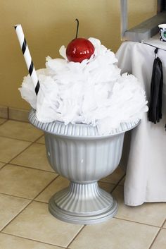 a white vase filled with tissue paper and a cherry