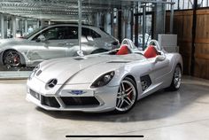 a silver sports car parked in a garage next to a white and red convertible vehicle