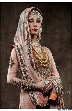 a woman in a bridal gown with jewelry on her head and hands behind her back