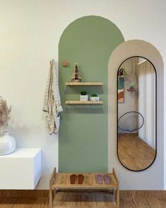 a green and white room with a bench, mirror and shelf on the wall next to it