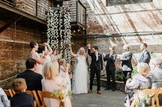 a bride and groom are walking down the aisle at their wedding ceremony in front of an old brick building