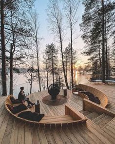 a person sitting on a wooden deck next to the water with trees in the background