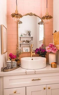 a bathroom sink sitting under a mirror next to a shelf with flowers and candles on it