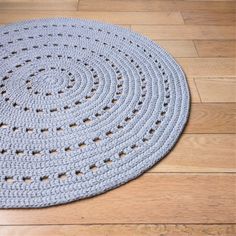 a crocheted rug is on the floor with wood floors in front of it