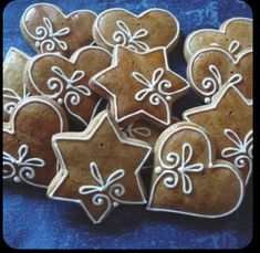 some cookies that are shaped like hearts and stars on a blue table cloth with white icing