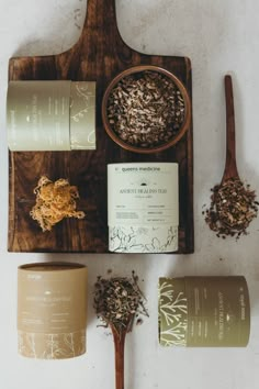 an assortment of teas and spices on a wooden tray next to two spoons