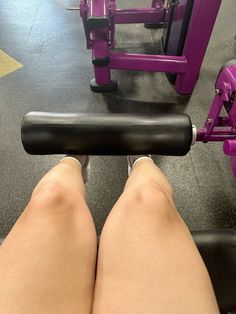 the legs of a person who is sitting on a bench with a bar in front of them