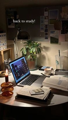 an open laptop computer sitting on top of a desk next to a candle and books