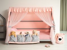 a pink canopy bed with three teddy bears in it and two other stuffed animals on the floor