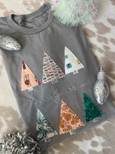 a t - shirt with sequins and christmas trees on it sitting on a bed