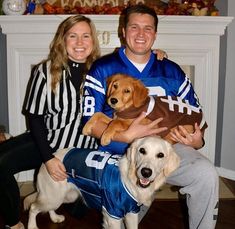 a man and woman sitting next to a dog in a football jersey holding a ball