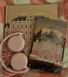 two books and headphones on a bed