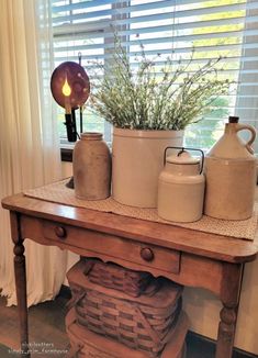 a wooden table topped with two vases and a potted plant on top of it