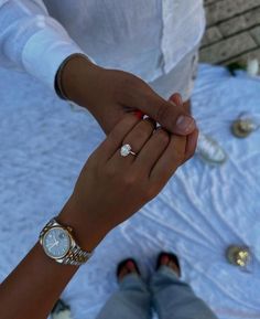 two people holding hands while sitting on a table