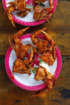 two plates with cooked food on them sitting on a wooden table next to each other