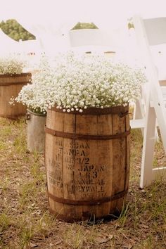 white flowers are in buckets on the side of a wooden barrel as an aisle