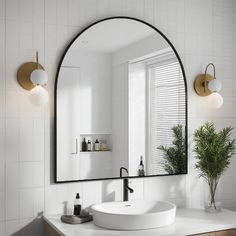 a white sink sitting under a large mirror in a bathroom next to a potted plant