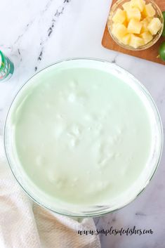 a glass bowl filled with green liquid next to a cutting board