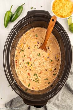 a crock pot filled with mexican chicken soup and garnished with jalapenos