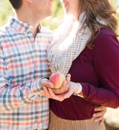 a man and woman holding an apple in their hands