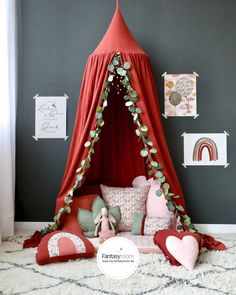 a bed with a canopy and pillows on the floor in front of a gray wall