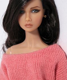 a close up of a doll wearing a pink sweater