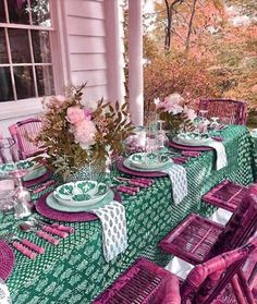 an outdoor table set with place settings and flowers in vases on the table cloth