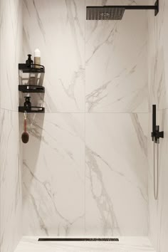 a bathroom with marble walls and flooring, including a shower head in the corner