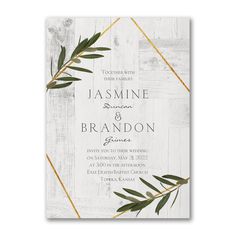 an elegant wedding card with greenery on the front and white wood in the background