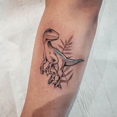 a tattoo on the leg of a person with a dinosaur design in black and grey