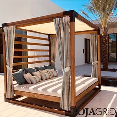 a bed sitting on top of a white tiled floor next to a palm tree in front of a house