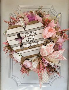 a heart shaped wreath with the words faith love grace written on it and pink flowers